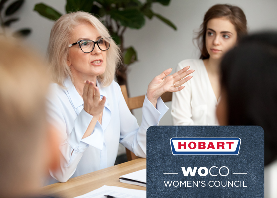 Schůzka v kanceláři zaměřená na HOBART Women’s Council (WOCO), iniciativu na podporu žen a rovnosti ve firmě. Na stole jsou dokumenty a psací potřeby.