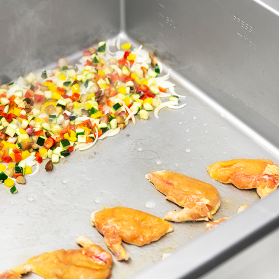 Vnitřek HOBART Precipan s nakrájenou zeleninou a opečenou drůbeží, multifunkční zařízení pro technologii vaření v profesionálních kuchyních.