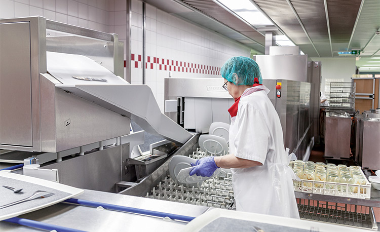 Ukázka HOBART FLOW Line autoLINE v moderní mycí kuchyni, automatický mycí systém s dopravníkem pro efektivní čištění talířů a sklenic, nerezová konstrukce pro hygienické a optimalizované procesy.