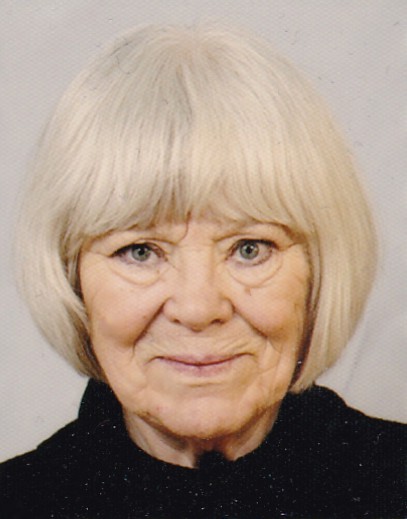 Portrét umělkyně Moniky Johannisson před světlým pozadím, v tmavém oblečení a se světle blonďatými vlasy po bradu. Klidná kompozice odráží její detailní malířský styl s využitím akrylu, tuše, uhlí a dalších výtvarných technik.