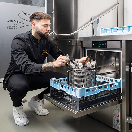 Pracovník vkládá lesklé příbory do rotačního koše BESTECK PREMIUM podstavné myčky HOBART pro dokonalé čištění.